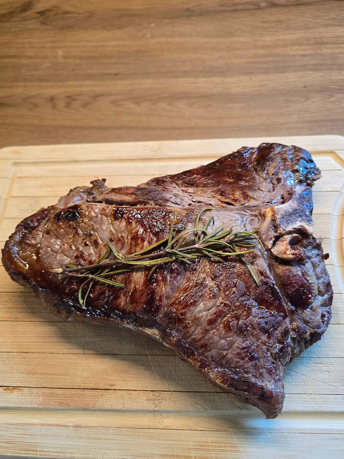 Chianina-Rind: Herkunft, Fleisch, IGP und richtige Zubereitung Fertiges Chianina-Steak auf dem Holzbrett mit Rosmarin